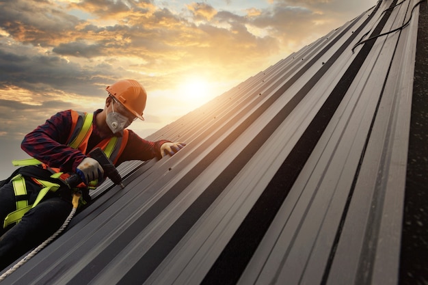 사진 roofer 건설 노동자는 새 지붕, 지붕 도구, 금속 시트로 새 지붕에 사용되는 전기 드릴을 설치합니다.