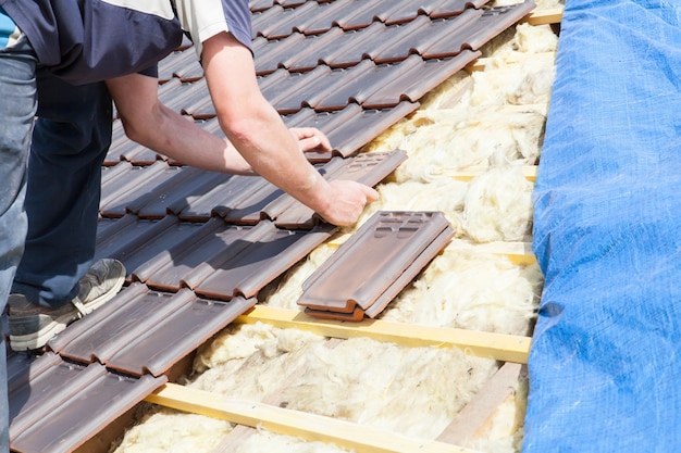Foto un roofer che pone le mattonelle sul tetto