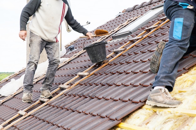 A roofer laying tile on the roof
