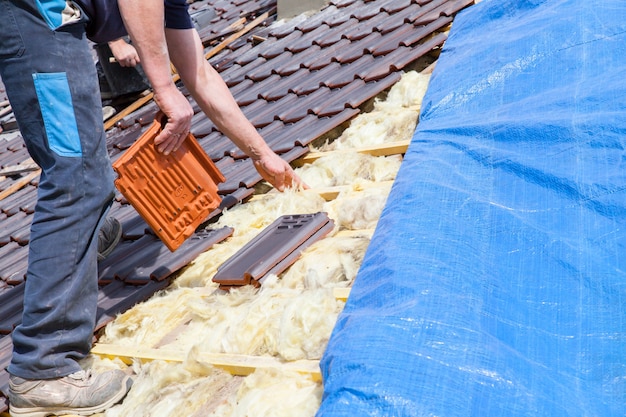 A roofer laying tile on the roof