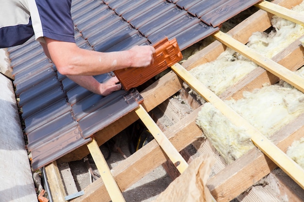 A roofer laying tile on the roof