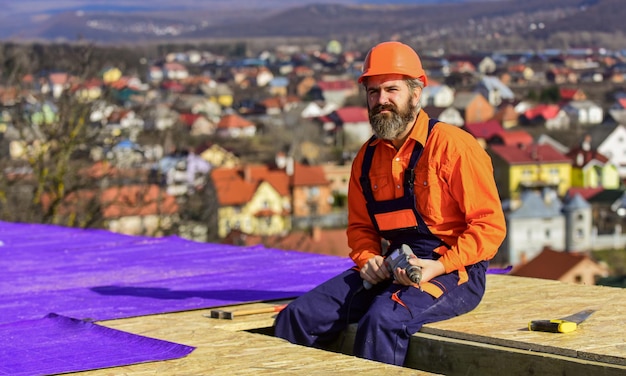 Roofer che lavora sulla struttura del tetto dell'edificio in cantiere. ispezione dell'uniforme di sicurezza dell'usura del roofer. roofer funzionante. strumento di lavoro per tetti. edilizia e impermeabilizzazione. esperto di sicurezza.