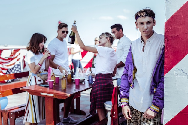 Rooftop party. Thoughtful stylish man leaning on the wall and looking forward