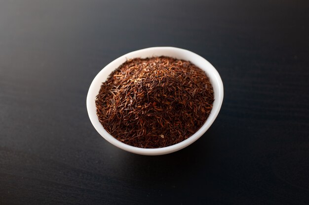 Rooibos tea on white plate on a wooden table.