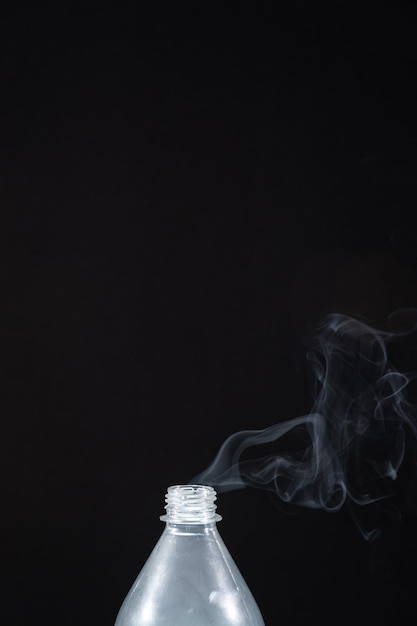 Foto rook komt uit een plastic fles tegen een zwarte achtergrond achtergrond voor halloween textuur mist ontwerpelement het concept van aromatherapie