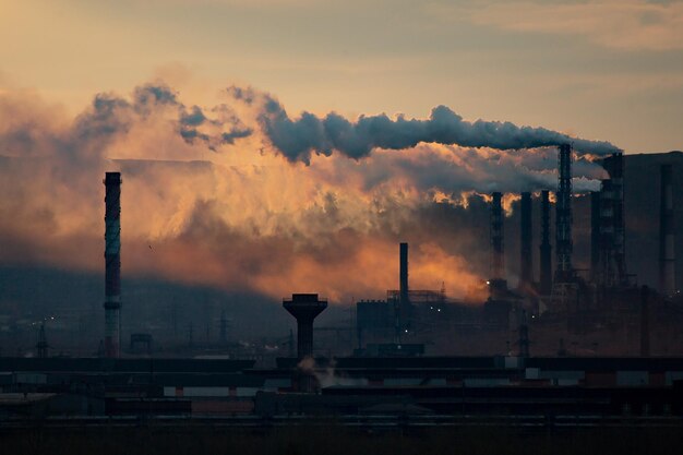 Rook uit de fabriek tegen de hemel bij zonsondergang