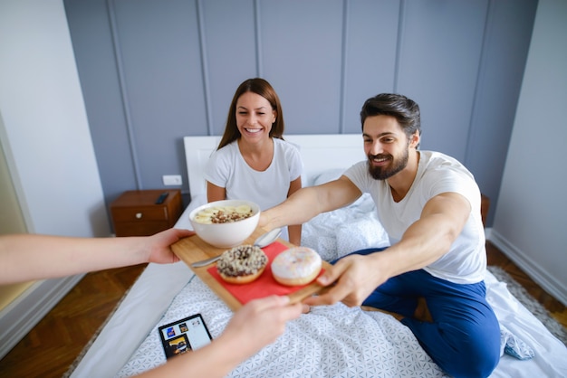 ルームサービス。ホテルの部屋で朝食を食べて幸せな若いカップル。幸せで恋に見えます。