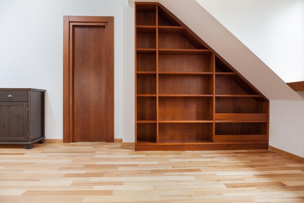 A room with a bookcase and a bookcase under the stairs.