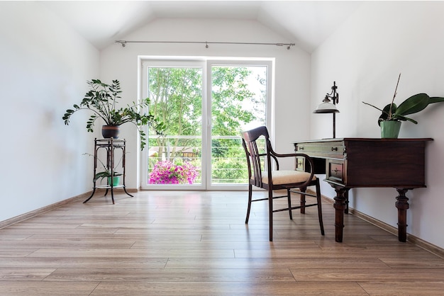 A room with a desk and a window with a balcony in the background