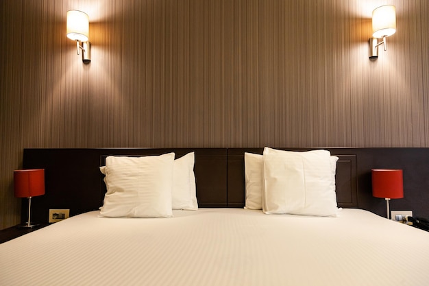 Room with large double bed illuminated by soft light coming from the lamps standing on bedside table