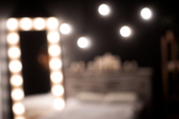 A room with a mirror that is surrounded by lights. Photo in bokeh
