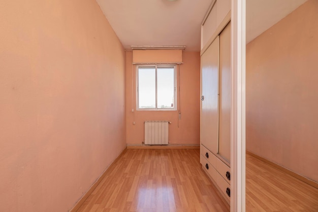 Room with mirrored sliding door wardrobe and glass window and aluminum sheet and pale pink painted walls