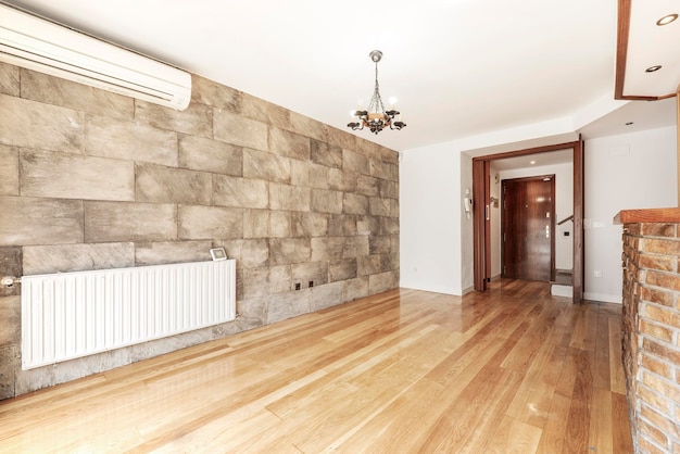 Room with slate tile wall radiator and air conditioner with oak flooring