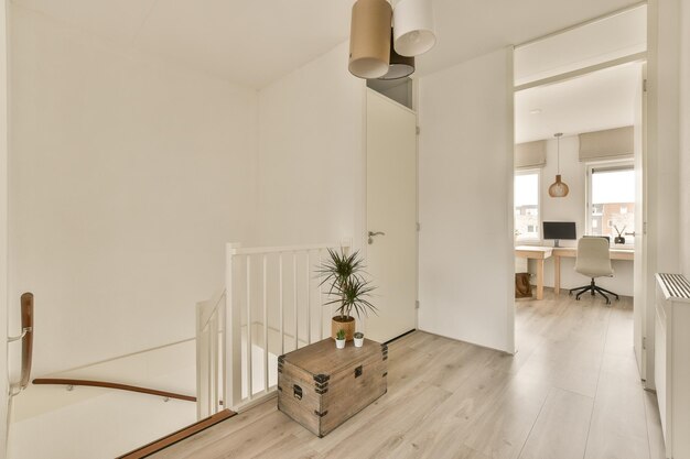 A room with white walls and wood flooring on the stairs there is an open door leading to another room