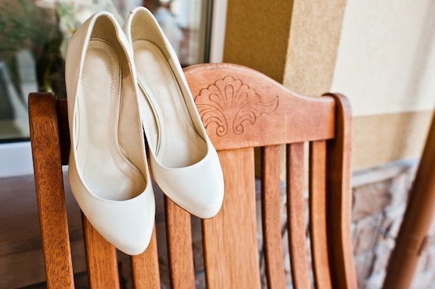 Roomhuwelijksschoenen van bruid op houten stoel