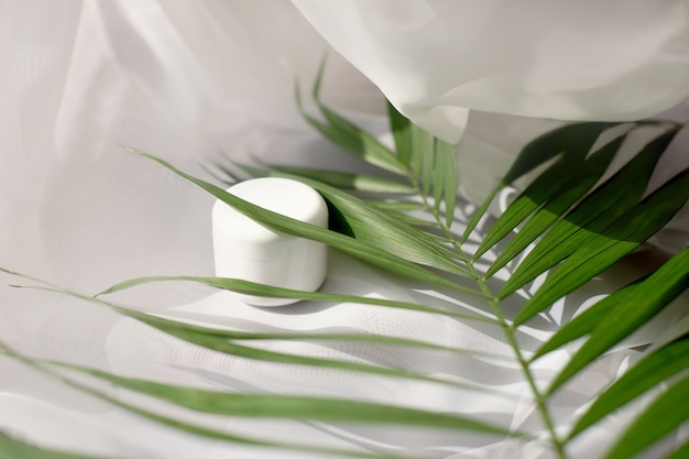 Roompotmodel op witte textielscène met groen tropisch palmblad