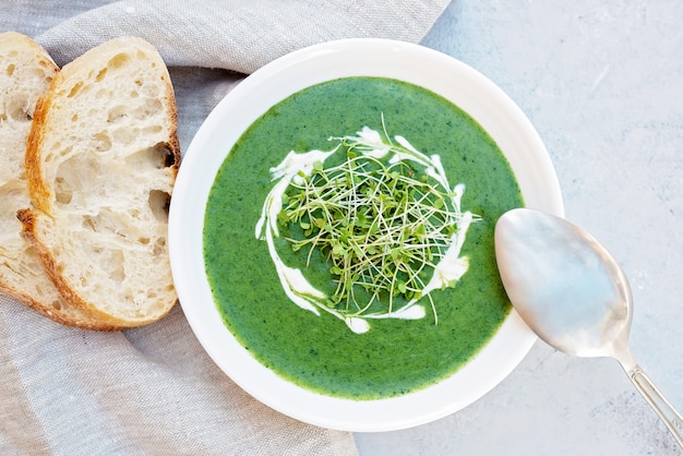 Roomsoep van verse spinazie met rucola microgroen in een witte plaat met ciabattabrood