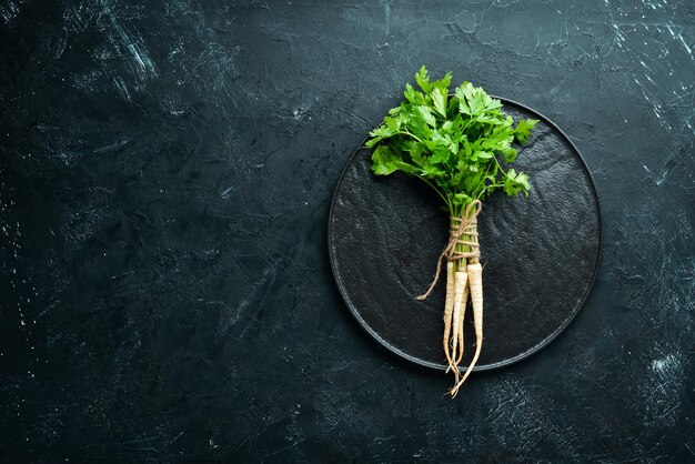 Root parsley and parsley on a black background Top view Free space for your text