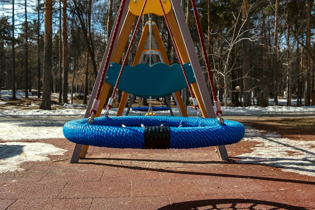 都市公園の遊び場でカラフルな空のブランコをロープ子供たちの娯楽と活動の視点