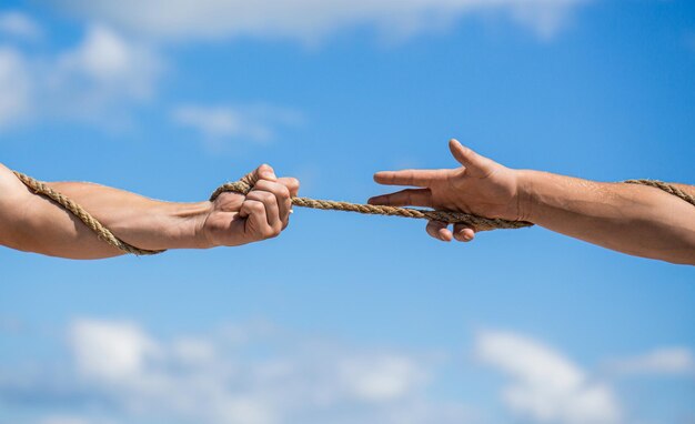 Rope cord hand holding a rope climbing rope strength and\
determination rescue help helping gesture or hands conflict tug of\
war