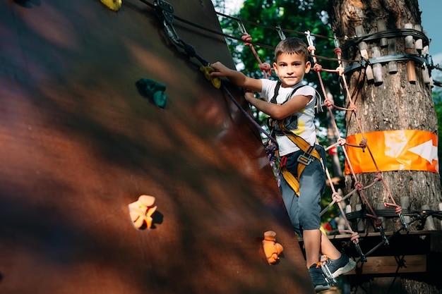 Foto parco della corda. il ragazzo supera l'ostacolo nel parco avventura.