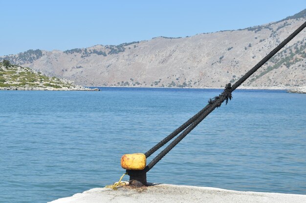 Foto una corda sulla roccia sul mare contro un cielo blu limpido