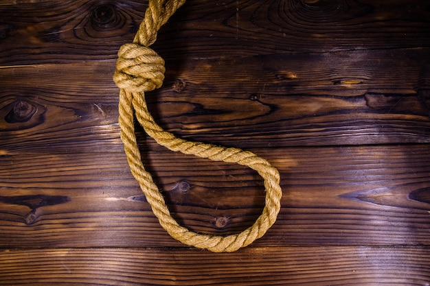 Rope with noose for the suicide on wooden background