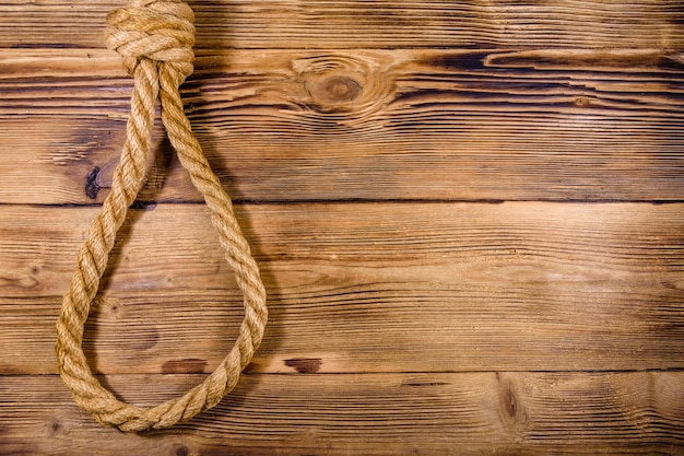 Веревка с петлей для самоубийства на деревянном фоне