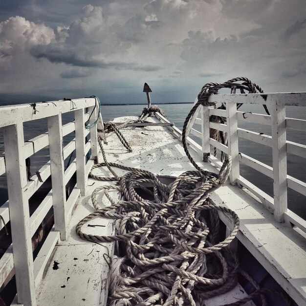 Ropes in boat on lake against sky