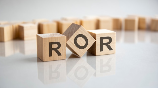 Photo ror - rate of return acronym concept on cubes, gray background