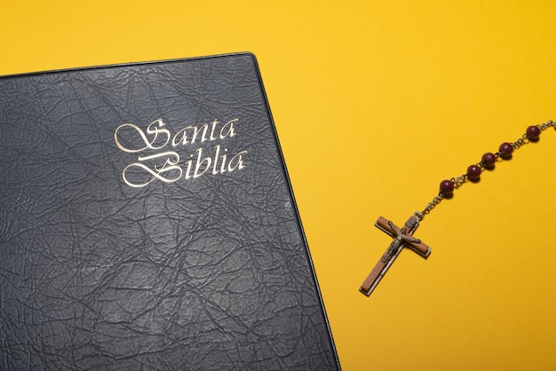 Photo rosary cross and santa biblia or holy bible on yellow