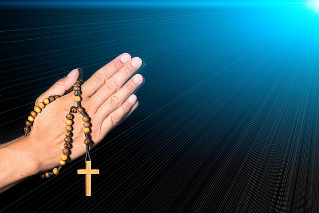 Rosary in hand on black background