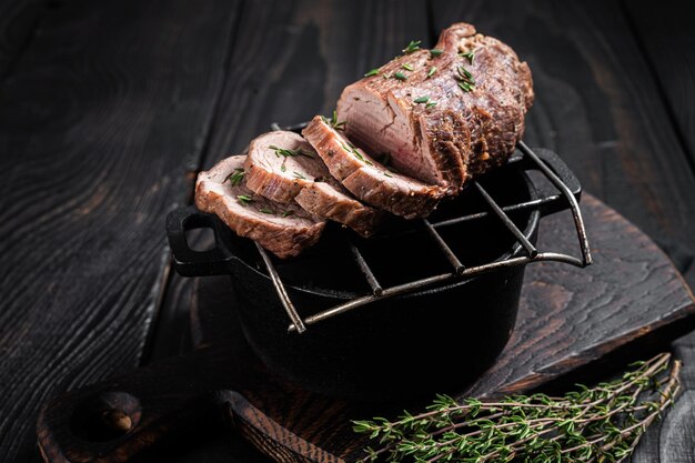Foto rosbief op een grill, ossenhaas gesneden vlees met kruiden. zwarte houten achtergrond. bovenaanzicht.