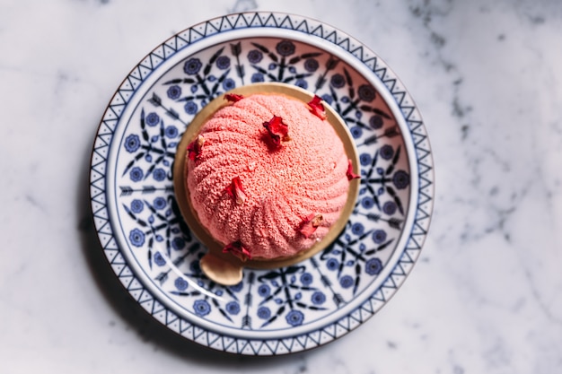 Фото Мусс из роз и личи торт украшен лепестками роз в сине-белой фарфоровой тарелке.