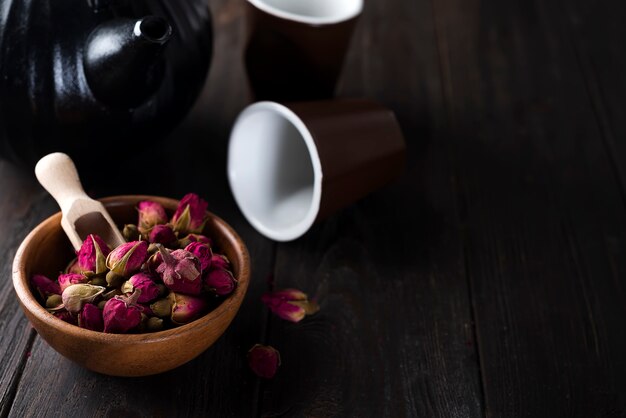 Rose buds tea on wooden bowl with tea pot