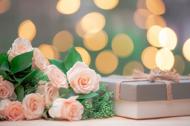 Rose flower, gift box, on wooden table with bokeh 