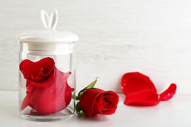 Rose flower in glass jar on light background