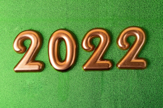 Rose gold numbers 2022 on the green background.