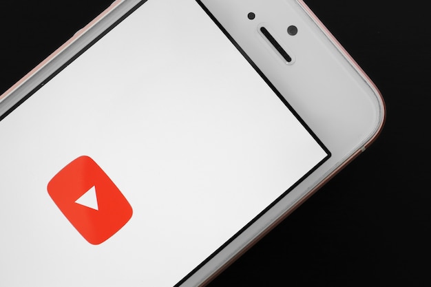 Rose gold-smartphone met youtube-app op het scherm tegen zwarte achtergrond