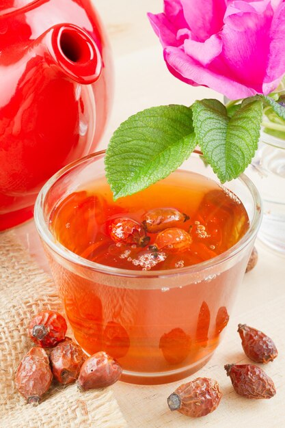 Фото Чай из шиповника, красный чайник и цветы шиповника
