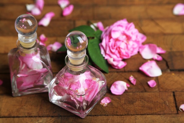 Rose oil in bottles on color wooden background