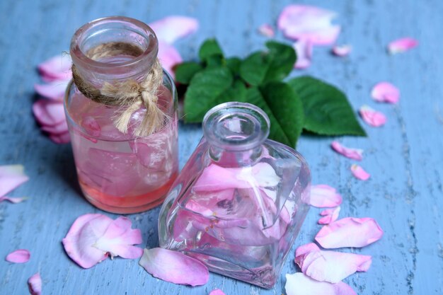 Rose oil in bottles on color wooden background