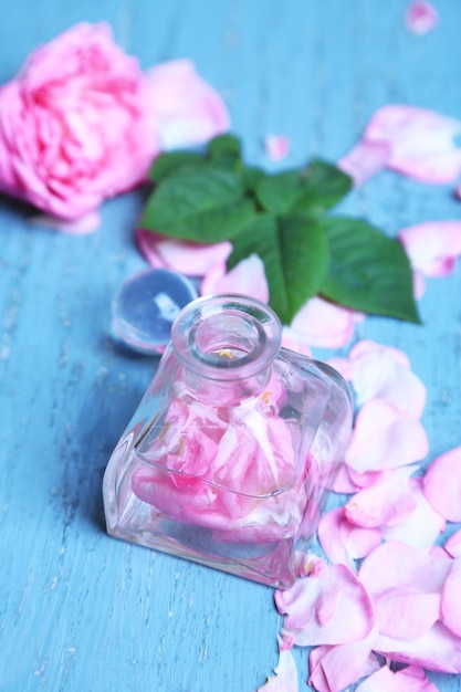 Rose oil in bottles on color wooden background