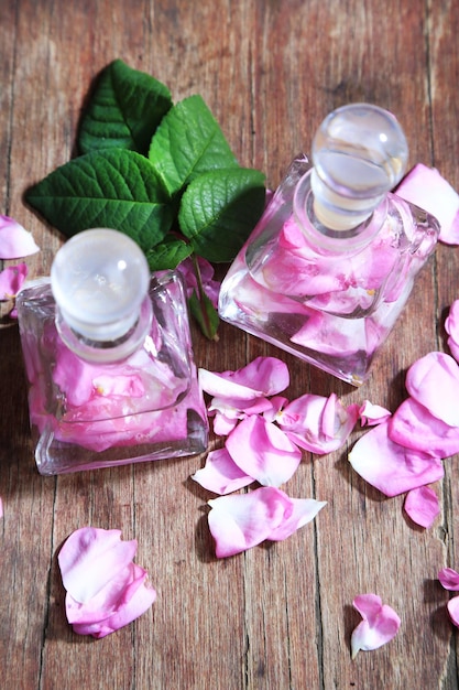 Rose oil in bottles on color wooden background