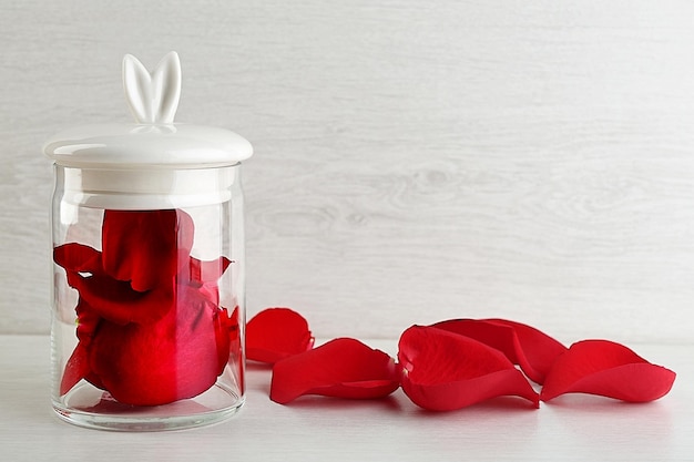 Rose petals in glass jar on light background