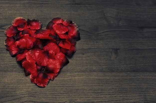 Rose petals heart on wooden table and copy space