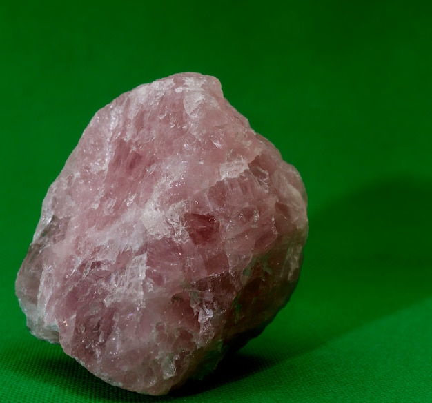 Rose quartz stone on a green background.