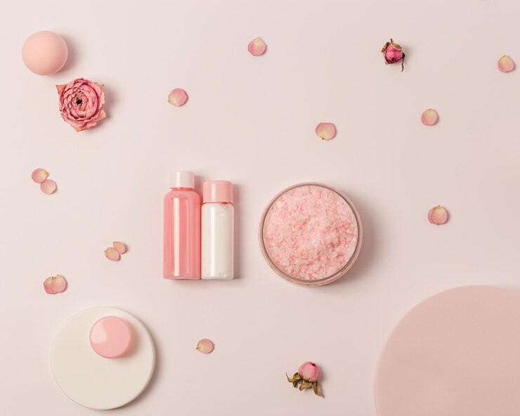 Rose scented sea salt in jar with small bottles shower gel soap and rose flowers on round podium Cosmetic product top view