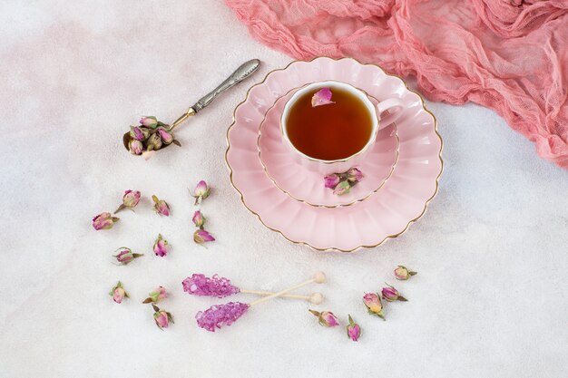 Photo rose tea in a pink cup, rose buds, an old spoon and pink sugar