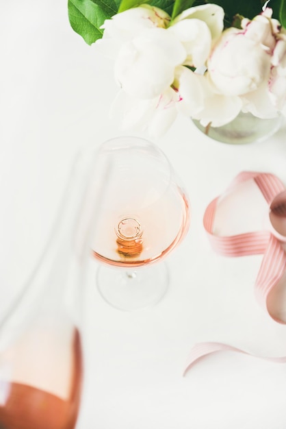 Rose wijn in glas roze lint pioen bloemen op tafel